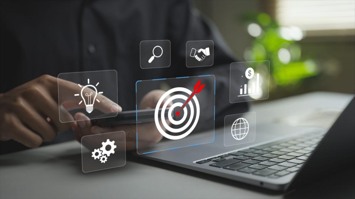 Mann analysiert Performance Marketing mit Smartphone und Laptop.
