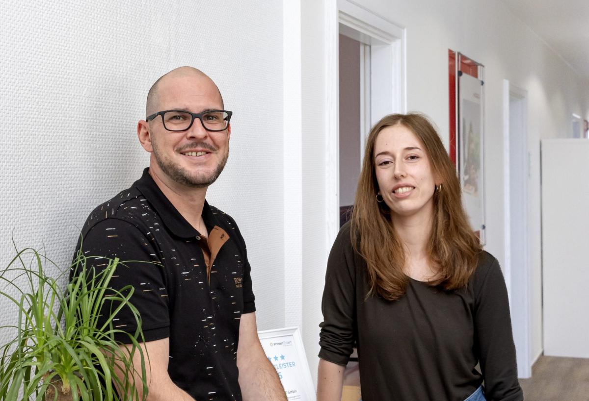Zwei Personen im Büro, die über KI-Sichtbarkeit sprechen.