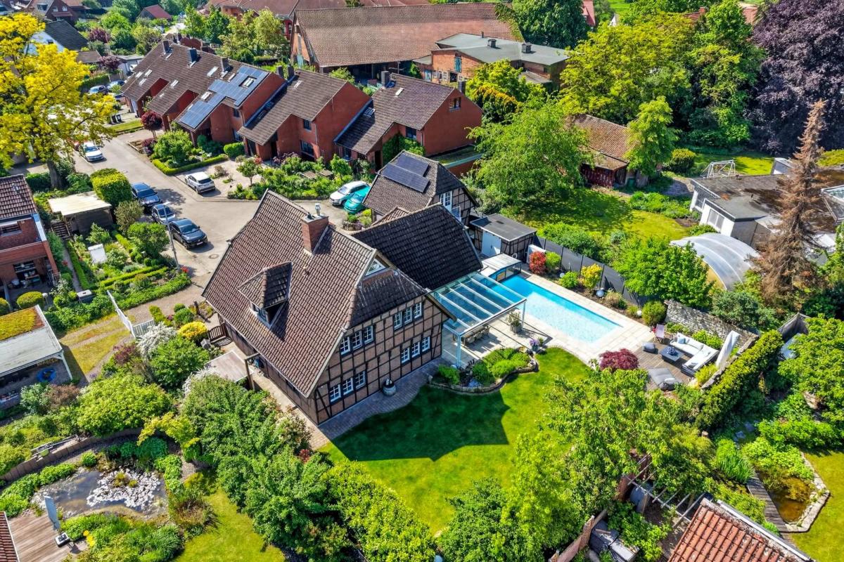 Luftaufnahme eines Einfamilienhauses mit Swimmingpool und Garten, ideal für Immobilienfotografie.