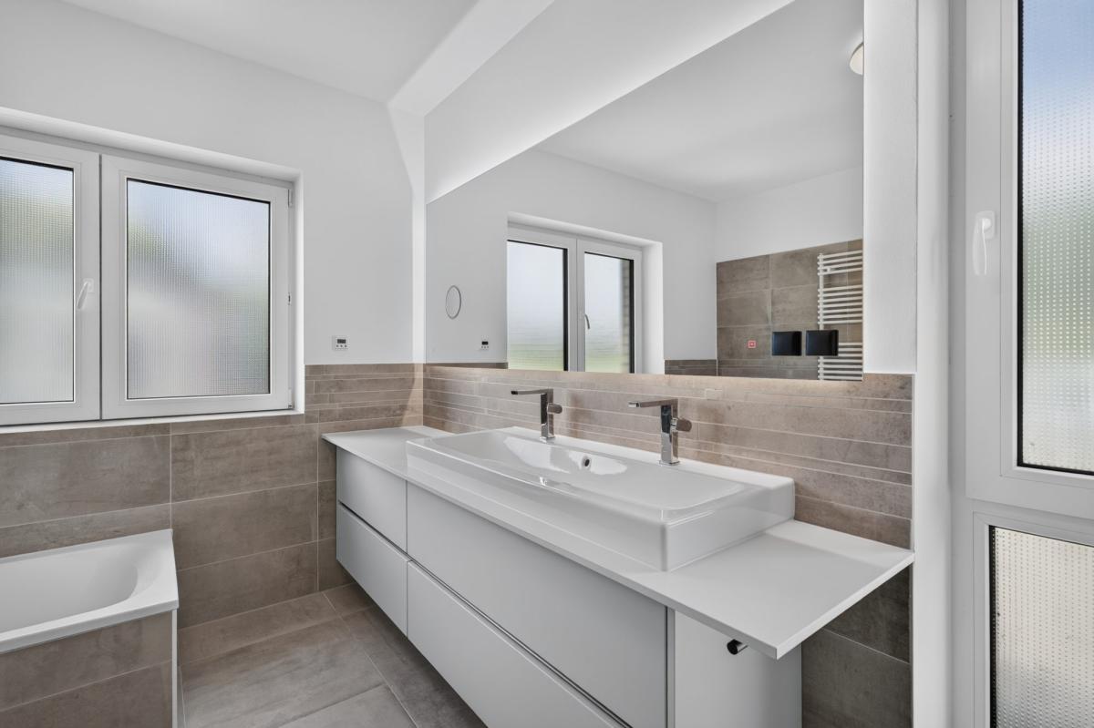 Modernes Badezimmer mit Doppelwaschbecken und großen Fenstern.