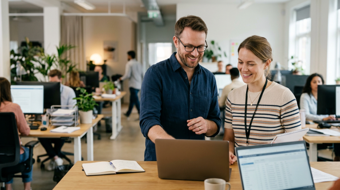 Zwei Mitarbeiter besprechen am Laptop das Thema KI-Cyberangriffe im Mittelstand.