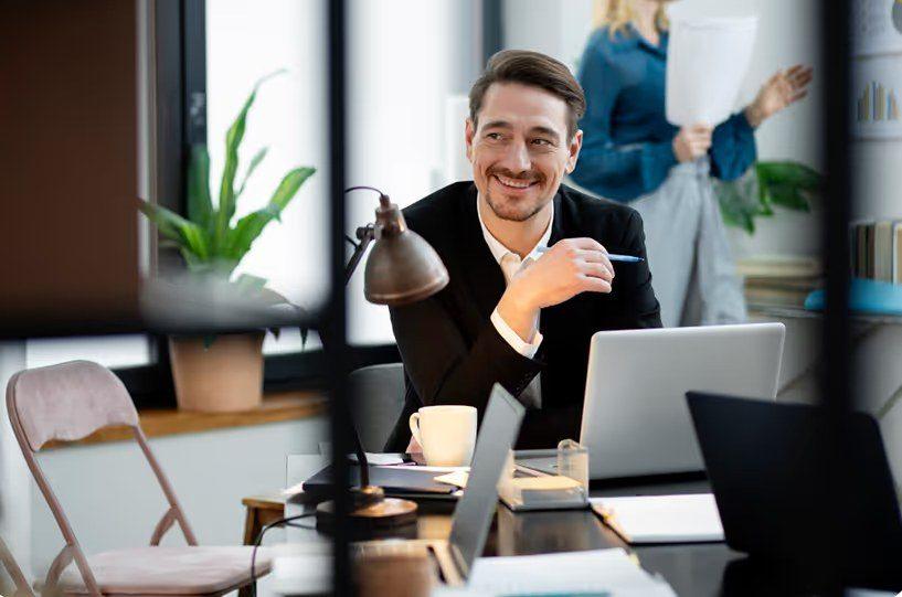 Ein Mann lächelt im Büro, während er über e-commerce liquidität steuern nachdenkt.