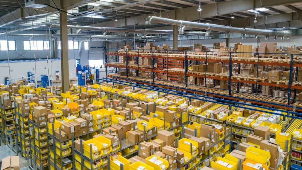 Lager mit gelben Paketen, die die E-Commerce Liquidität beeinflussen.