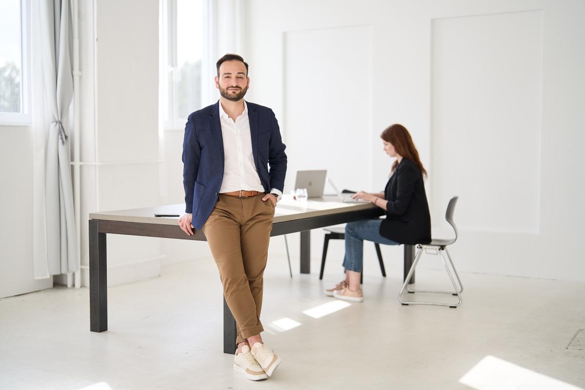 Ein Chef steht entspannt vor einem Tisch im Büro und vermittelt klare Grenzen.
