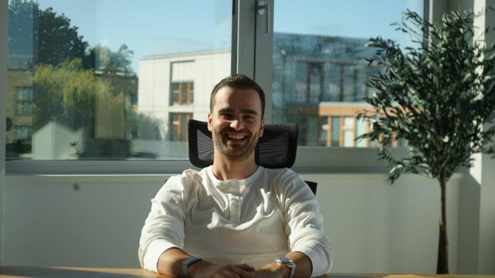 Ein lächelnder Mann im Büro sitzt und denkt über den Steuerberaterwechsel nach.