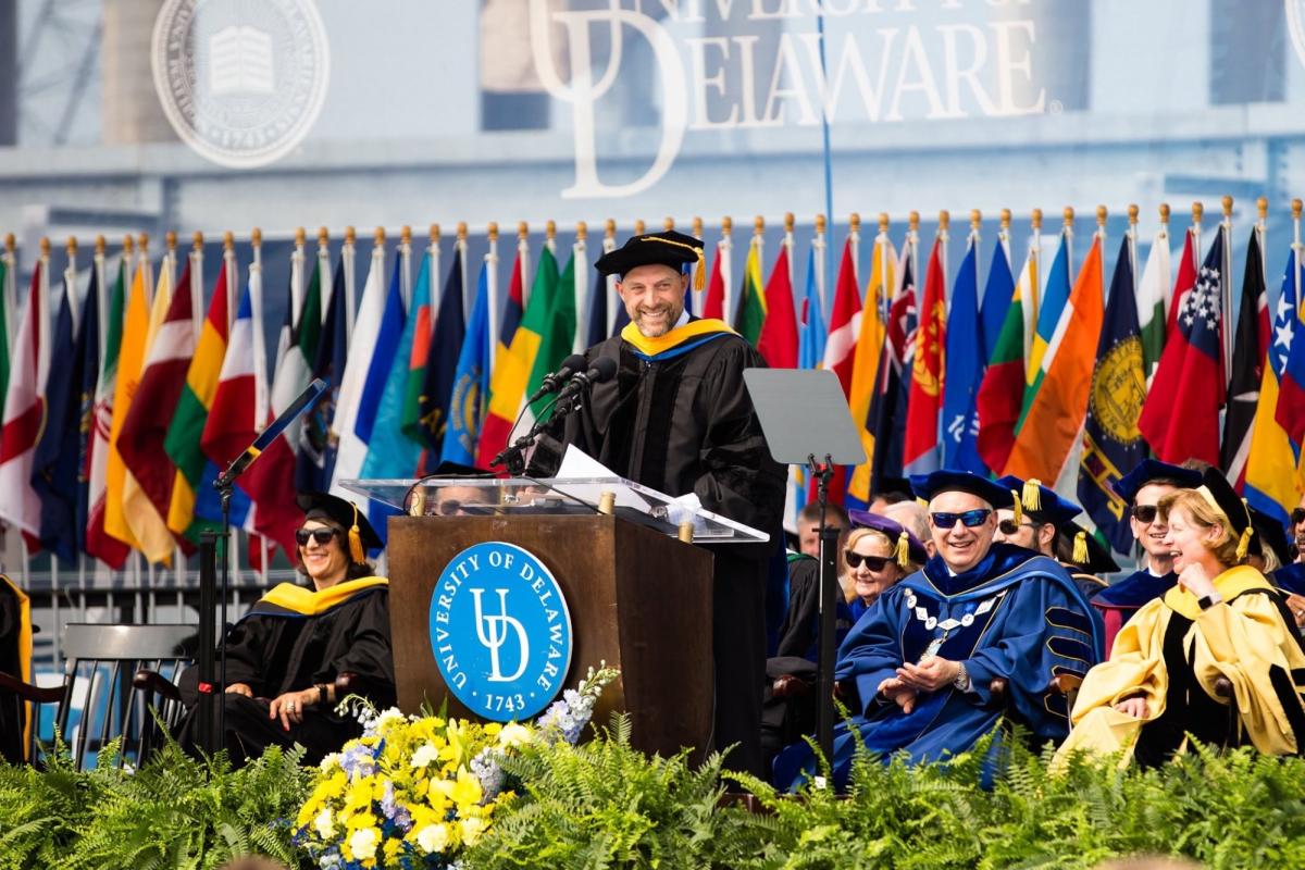 Feierliche Absolventenfeier an der University of Delaware mit Flaggen und Redner.
