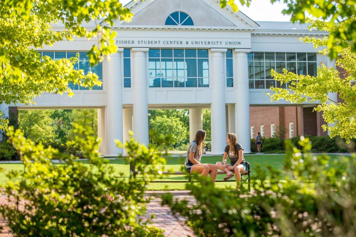Zwei Studierende besprechen ihre Zulassungschancen in den USA vor einem Universitätsgebäude.