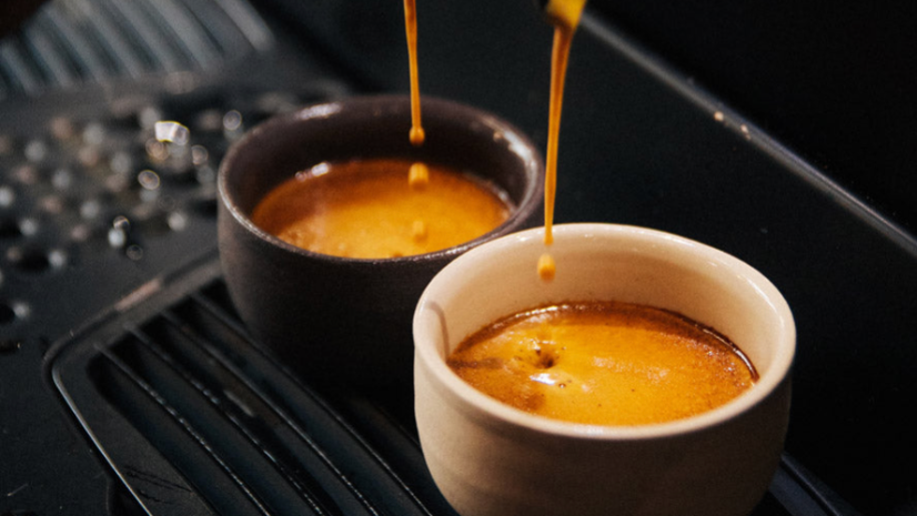 Frisch zubereitete Espressi in zwei Tassen als Zeichen für Kaffeelieferant für Unternehmen.