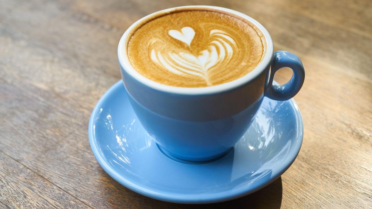 Ein schöner Kaffee mit Herzschäumen in einer blauen Tasse, ideal für besten Kaffeegenuss.