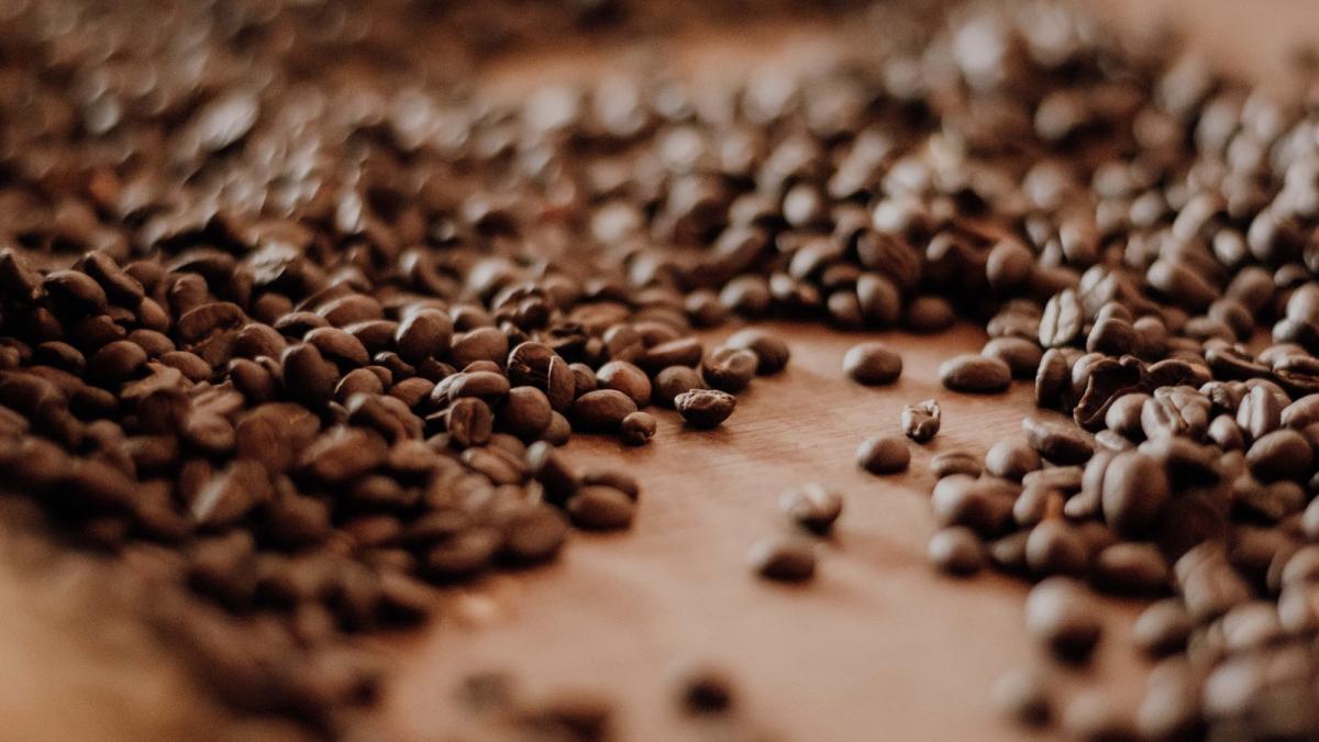 Nahaufnahme von milde Kaffee Bohnen auf einer Holzoberfläche.
