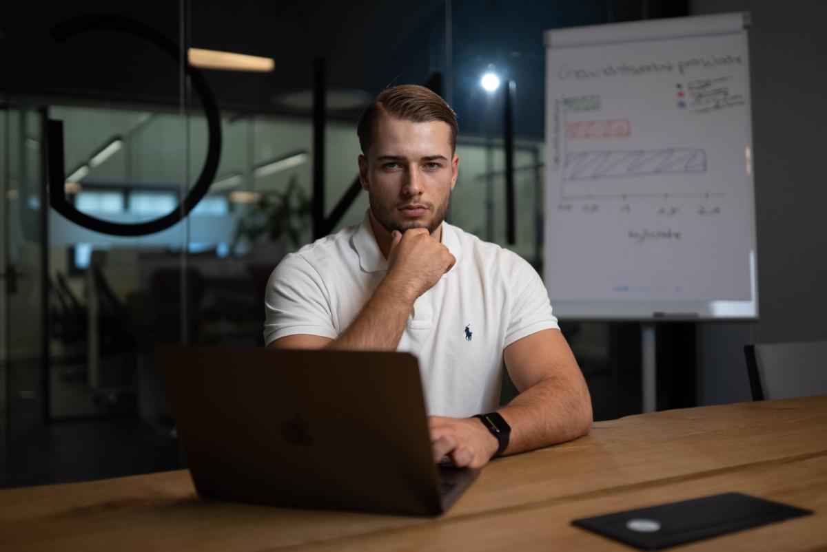 Mann sitzt am Laptop und wirkt nach der Arbeit müde.