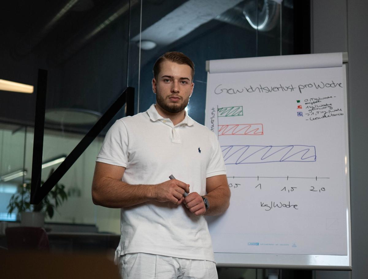 Mann präsentiert eine Grafik zum Thema 20 Stunden Fasten vor einem Flipchart.