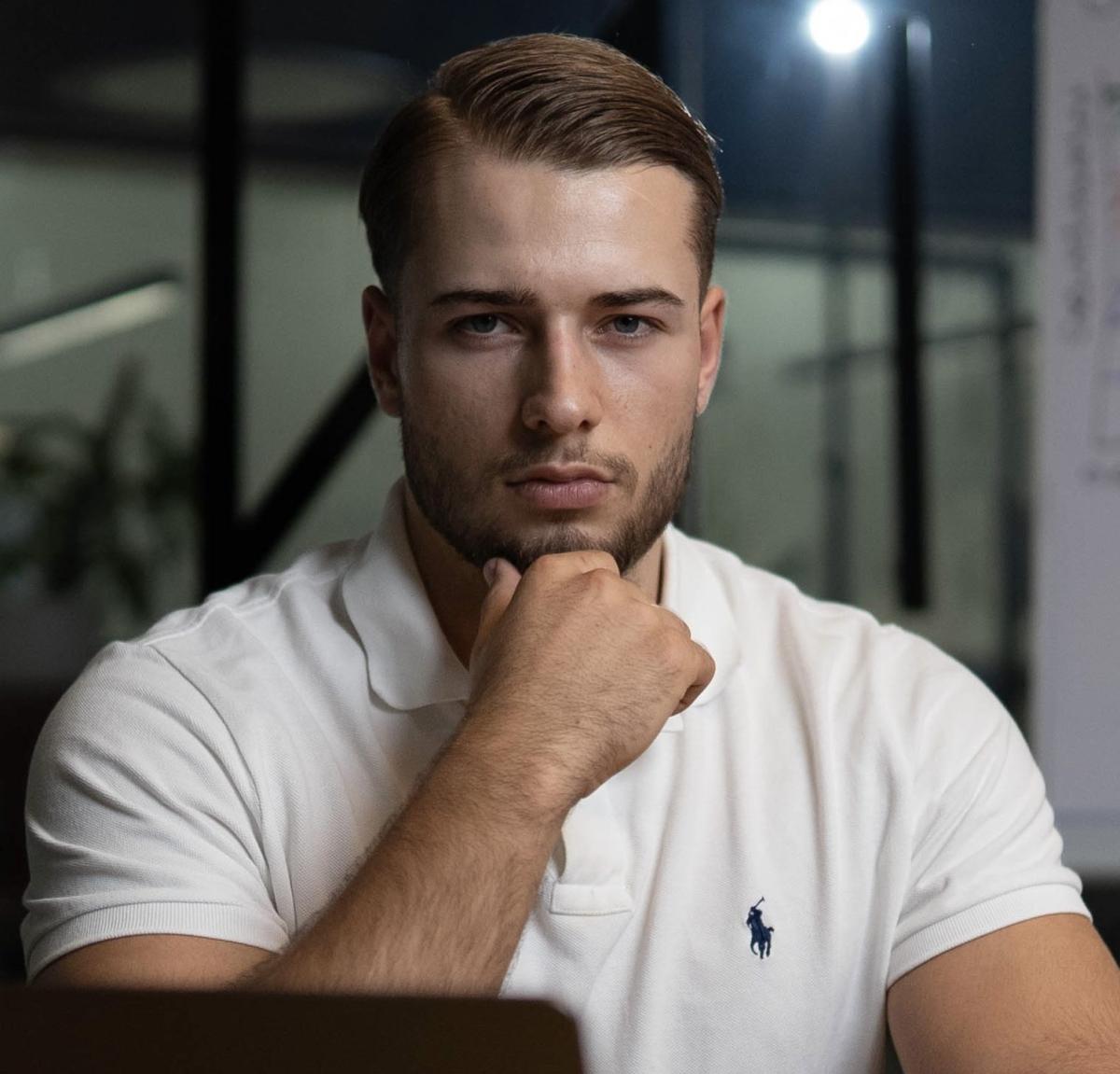 Ein nachdenklicher Mann in einem weißen Poloshirt, der über Lebensmittel zur Gewichtsabnahme reflektiert.