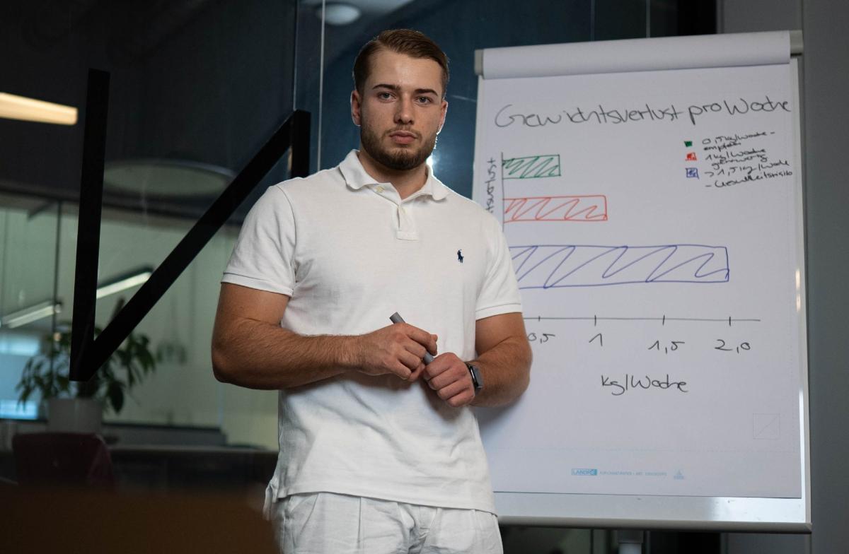 Mann steht vor Präsentationsfolie zum Thema 10 kg abnehmen.