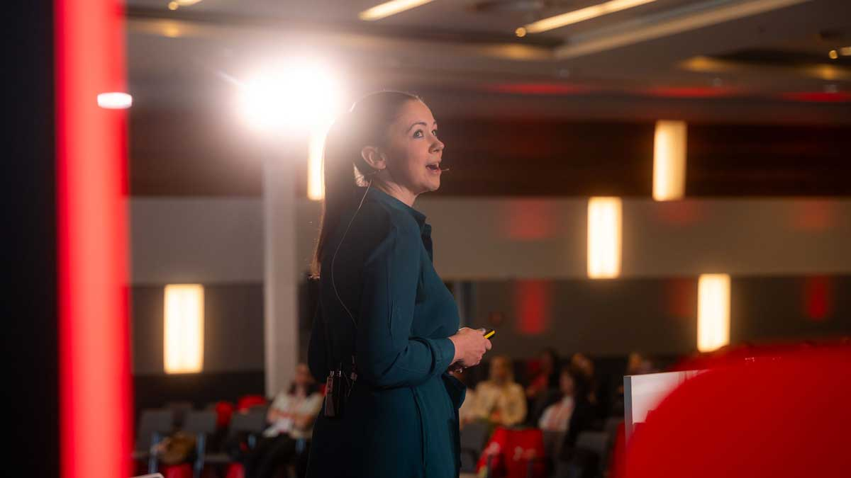Eine Rednerin spricht über verkaufsfähige Vermögensverwaltung auf einer Konferenz.