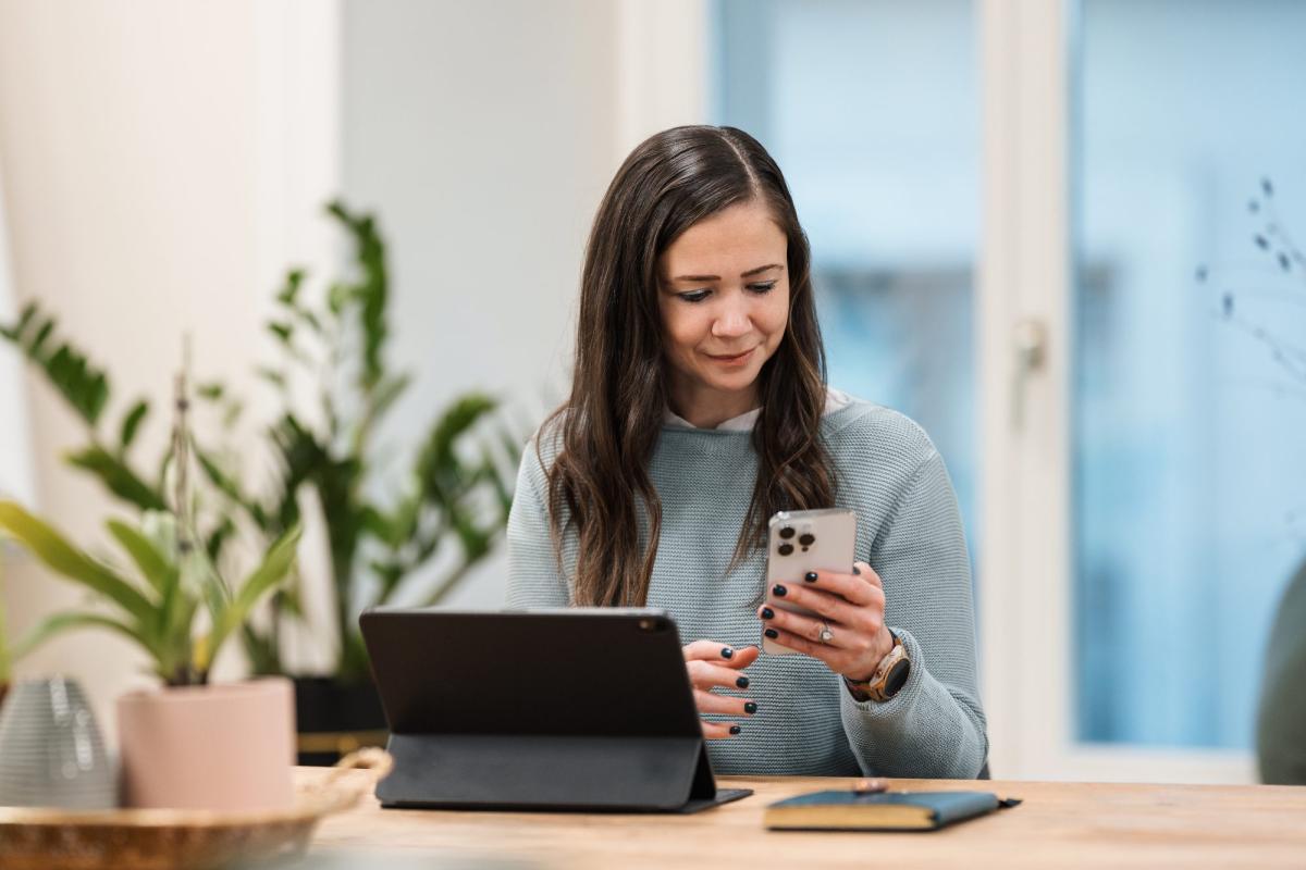 Eine Frau überprüft auf ihrem Smartphone Informationen über Vermögensverwalter verkaufen.