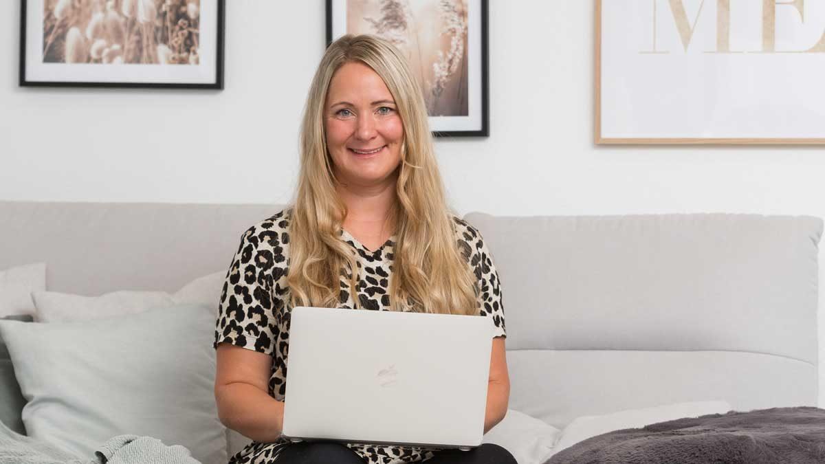Eine Frau mit Laptop sitzt gemütlich und arbeitet an der Ordnung in ihren Finanzen.