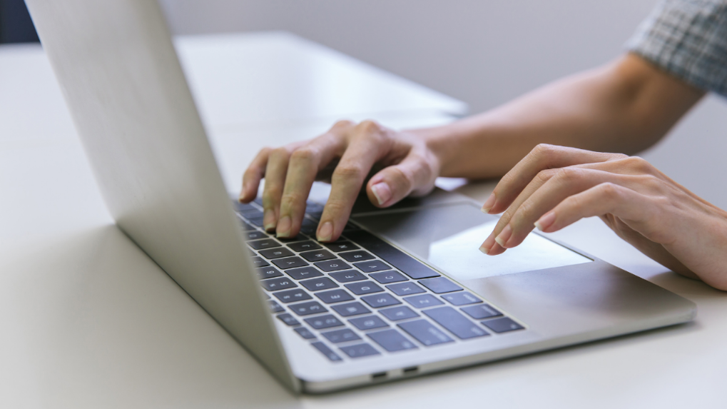 Person tippt an einem Laptop zum Webseiten-Aufbau im Arbeitsschutz.