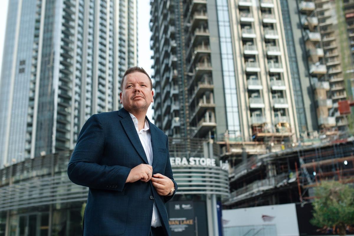 Ein Mann im Anzug steht vor modernen Hochhäusern in Dubai – passend zum Thema Makler Dubai.