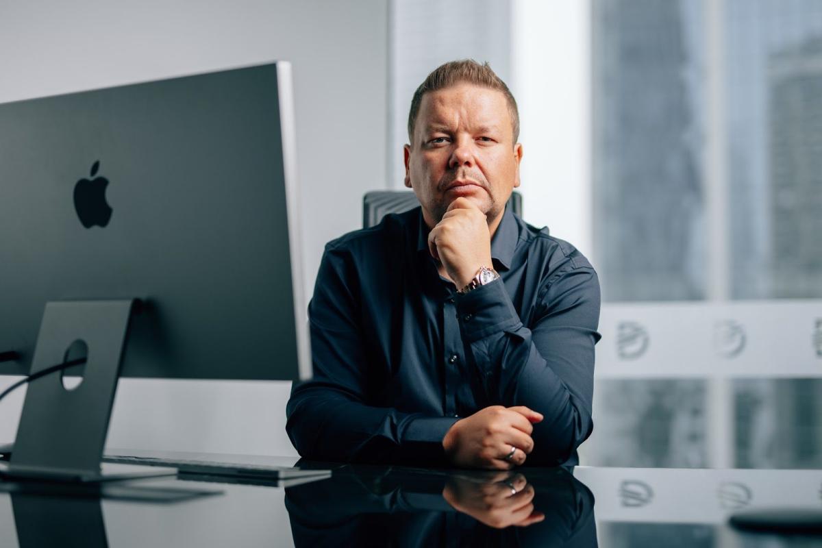 Mann sitzt nachdenklich am Schreibtisch vor einem iMac und veranschaulicht die Entscheidung, eine Dubai Immobilie zu finanzieren.