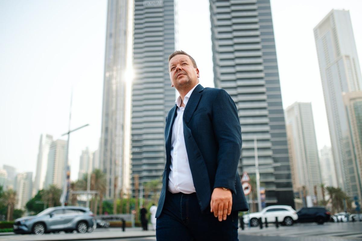 Ein Mann im Anzug steht vor modernen Hochhäusern in Dubai – passend zum Thema Dubai Immobilie finanzieren.