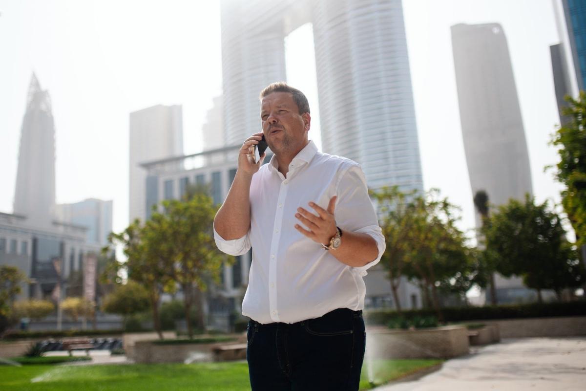 Ein Mann telefoniert vor modernen Hochhäusern in Dubai – passend zum Thema Dubai-Mieteinnahmen in der Steuererklärung.