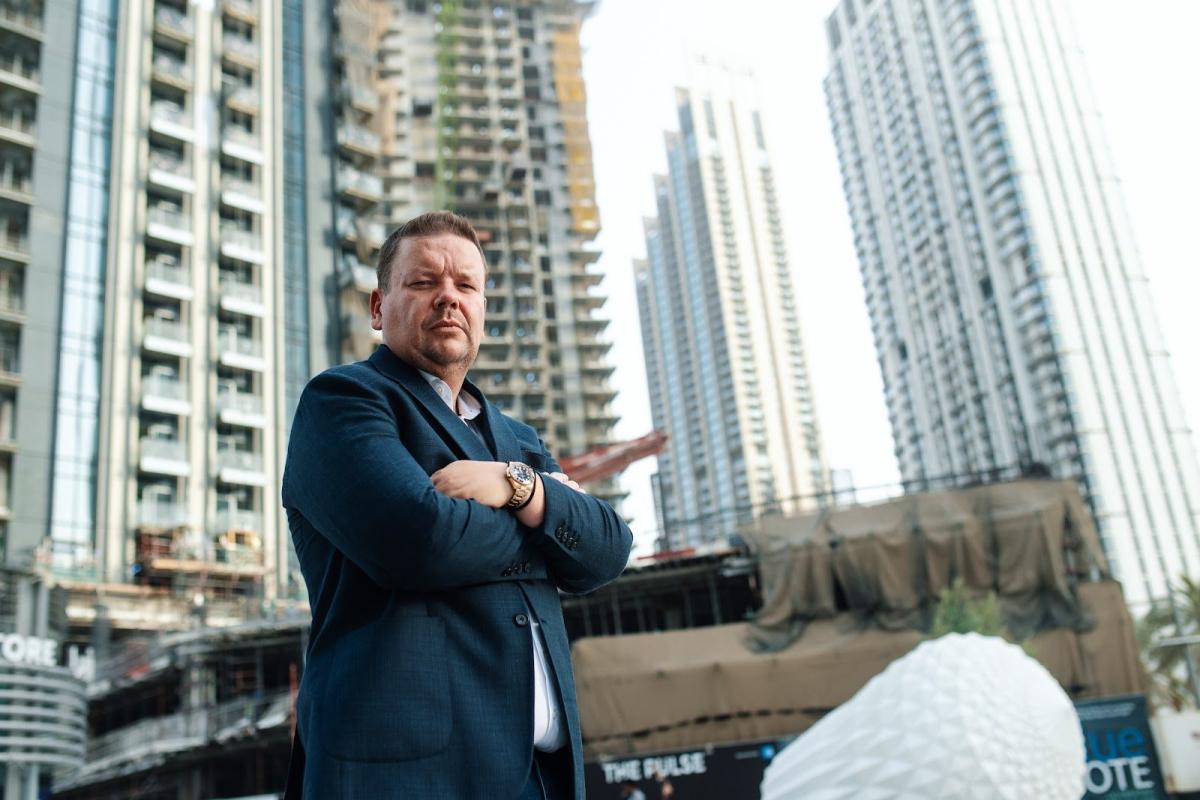Ein Mann steht vor modernen Hochhäusern; Dubai-Mieteinnahmen sind Thema des Steuerartikels.