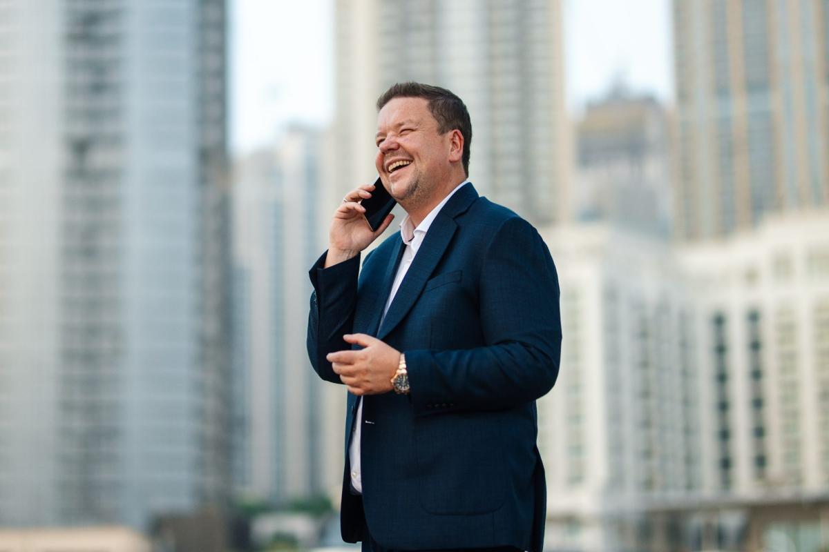 Ein Mann telefoniert lächelnd in Dubai, während er Informationen zur Immobilie in Dubai kaufen einholt.