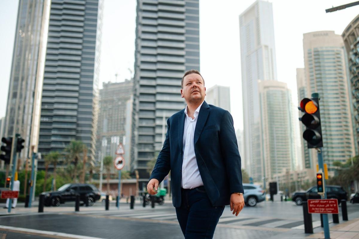 Mann geht durch Dubai, während er sich mit Kaufpreisaufteilung beschäftigt.