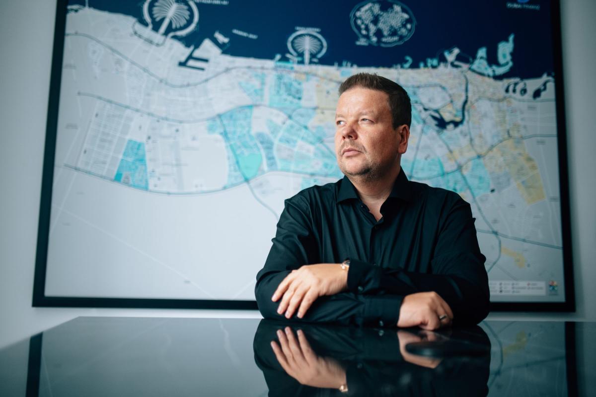 Eugen Zimbelmann diskutiert den Dubai Immobilienmarkt 2026 vor einer Stadtkarte.