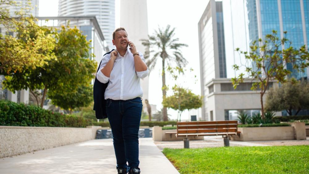 Ein Mann im Park in Dubai, der telefoniert, während Expats die Stadt verlassen.