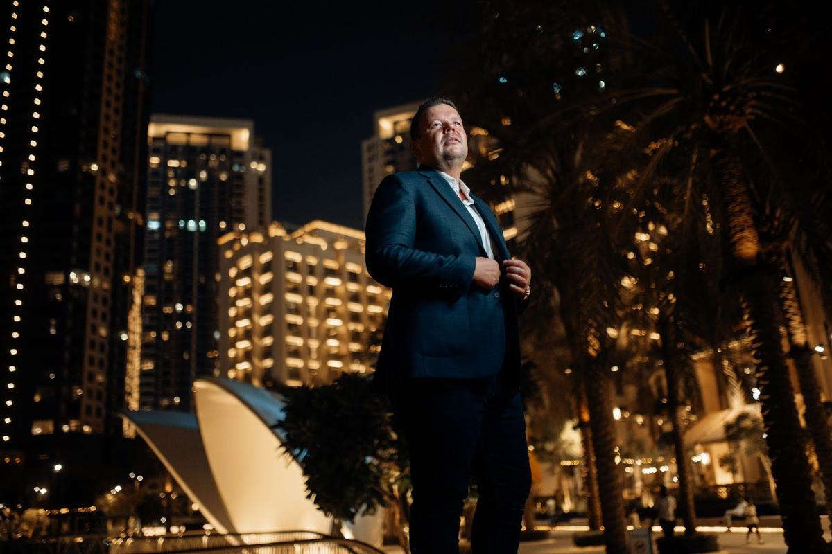 Mann in Anzug steht in Dubai vor leuchtenden Off-Plan Immobilien.