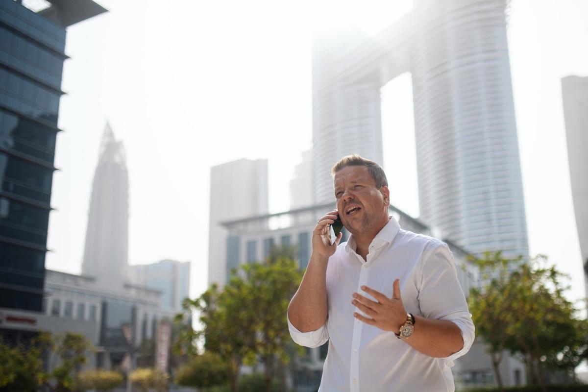 Ein Mann telefoniert vor der Skyline von Dubai – passend zum Thema Wohnung in Dubai vermieten.