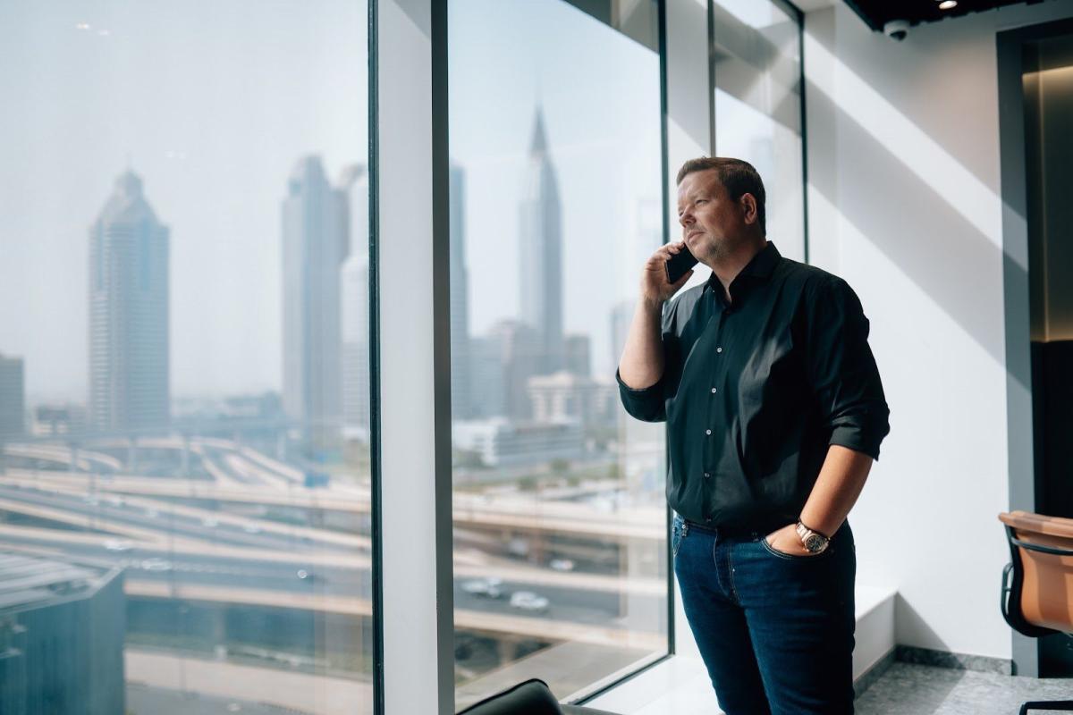 Mann spricht am Telefon mit Blick auf Dubai, während er ein Bankkonto in Dubai eröffnen möchte.