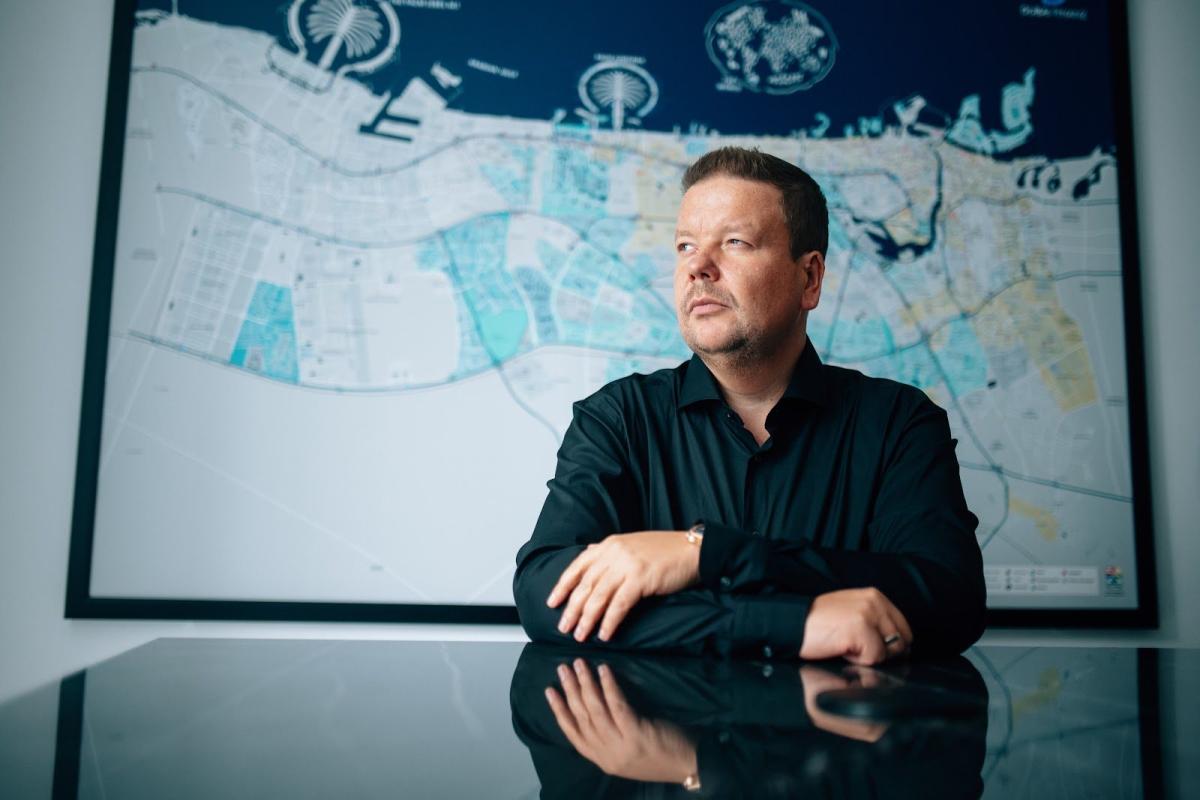 Eugen Zimbelmann erläutert die Hypothekenzinsen in Dubai vor einer Stadtkarte.