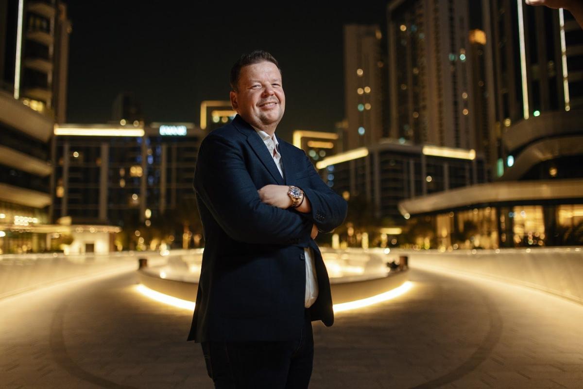 Eugen Zimbelmann steht vor modernen Gebäuden in Dubai, während er über den Kauf von Immobilien spricht.