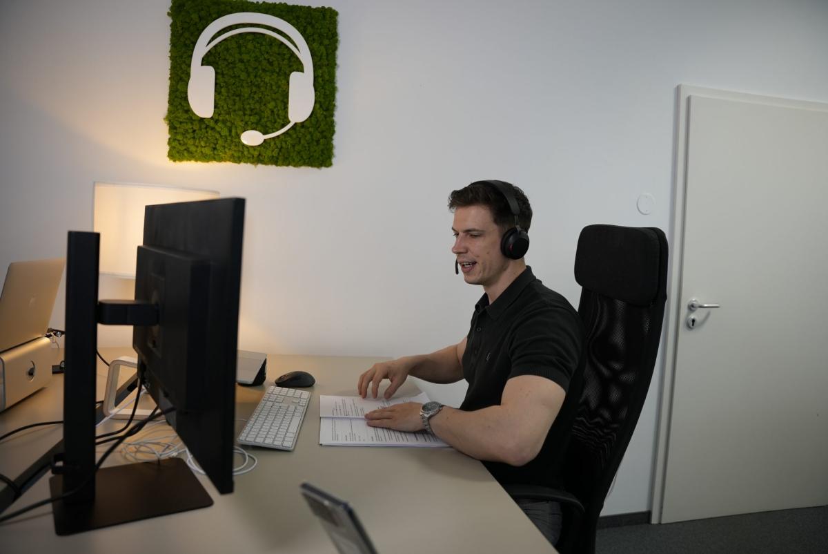 Mann mit Headset am Computer während einer Kaltakquise, um Vertrauen zu gewinnen.