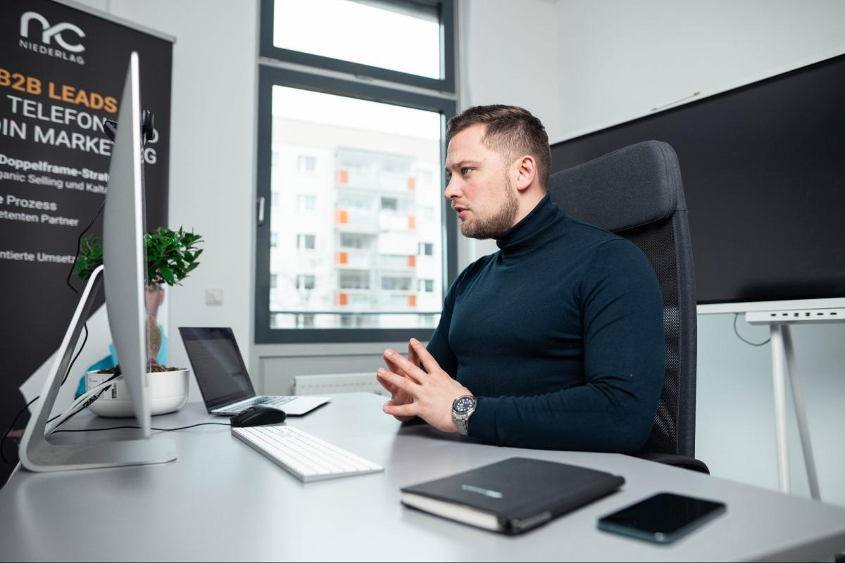 Mann am Schreibtisch in einem Büro, der an Kaltakquise und Vertrauensaufbau arbeitet.