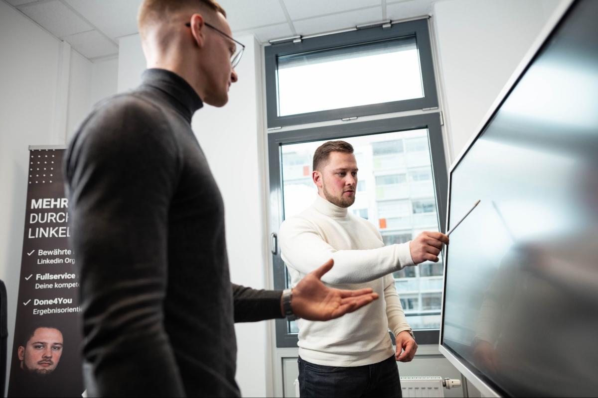 Zwei Personen diskutieren über B2B-Kontaktdaten während einer Präsentation.