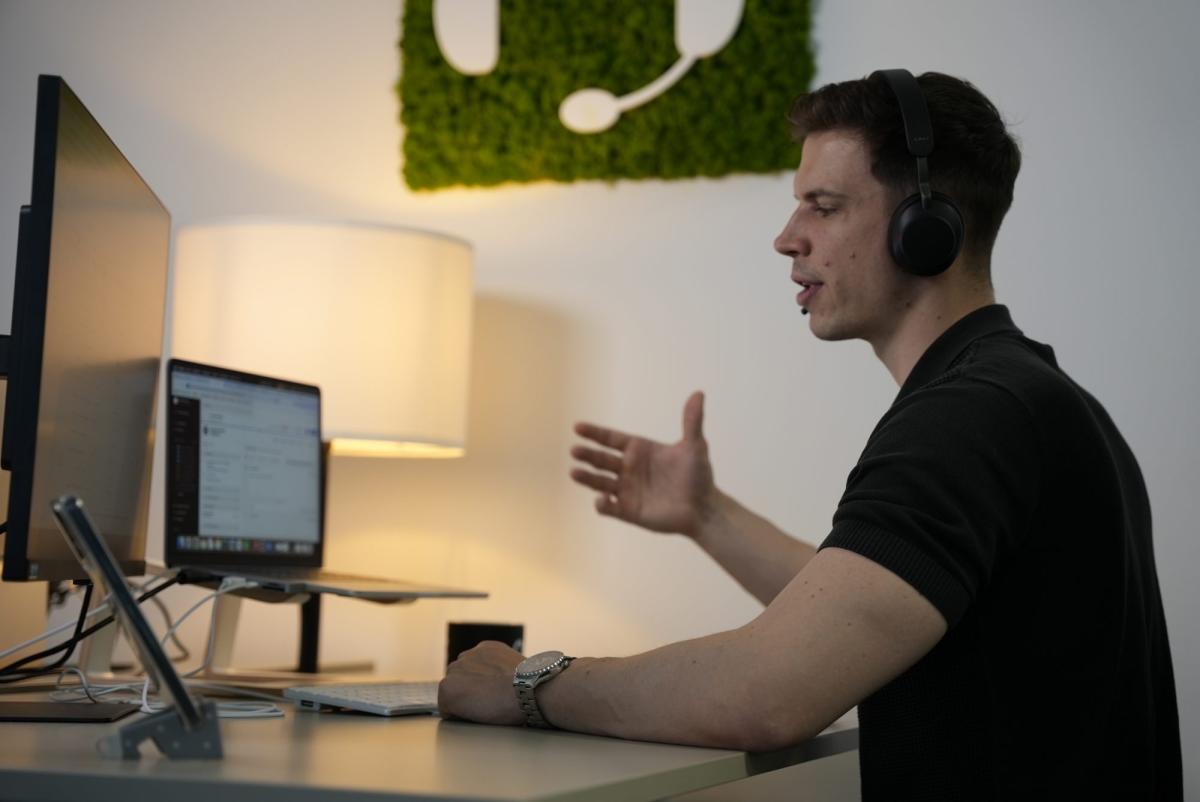Mann mit Headset spricht am Computer während der Kaltakquise.