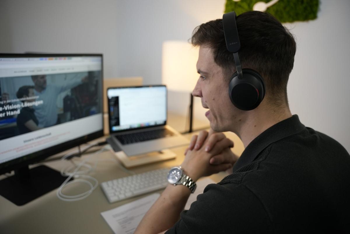 Mann mit Kopfhörern führt ein Kaltakquise-Gespräch mit Storytelling am Computer.
