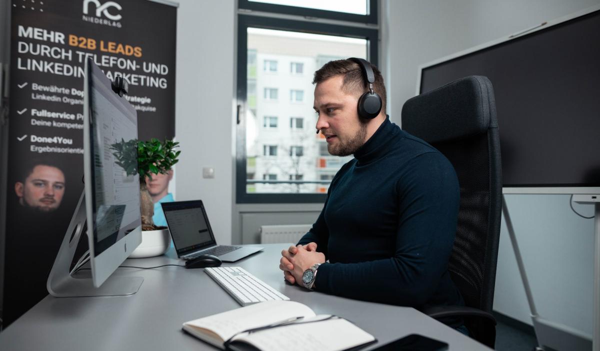 Mann mit Headset konzentriert am Schreibtisch während einer Besprechung zu Kaltakquise Tipps.