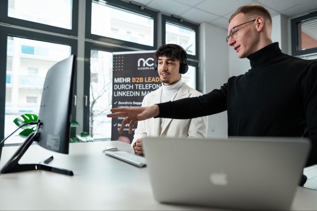Zwei Personen führen ein Verkaufsgespräch und analysieren am Computer, um Verkaufsgespräche effektiv zu führen.