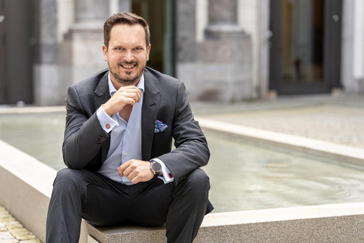 Mann im Anzug sitzt am Wasserspiel und spricht über Match Group und Dating Apps.
