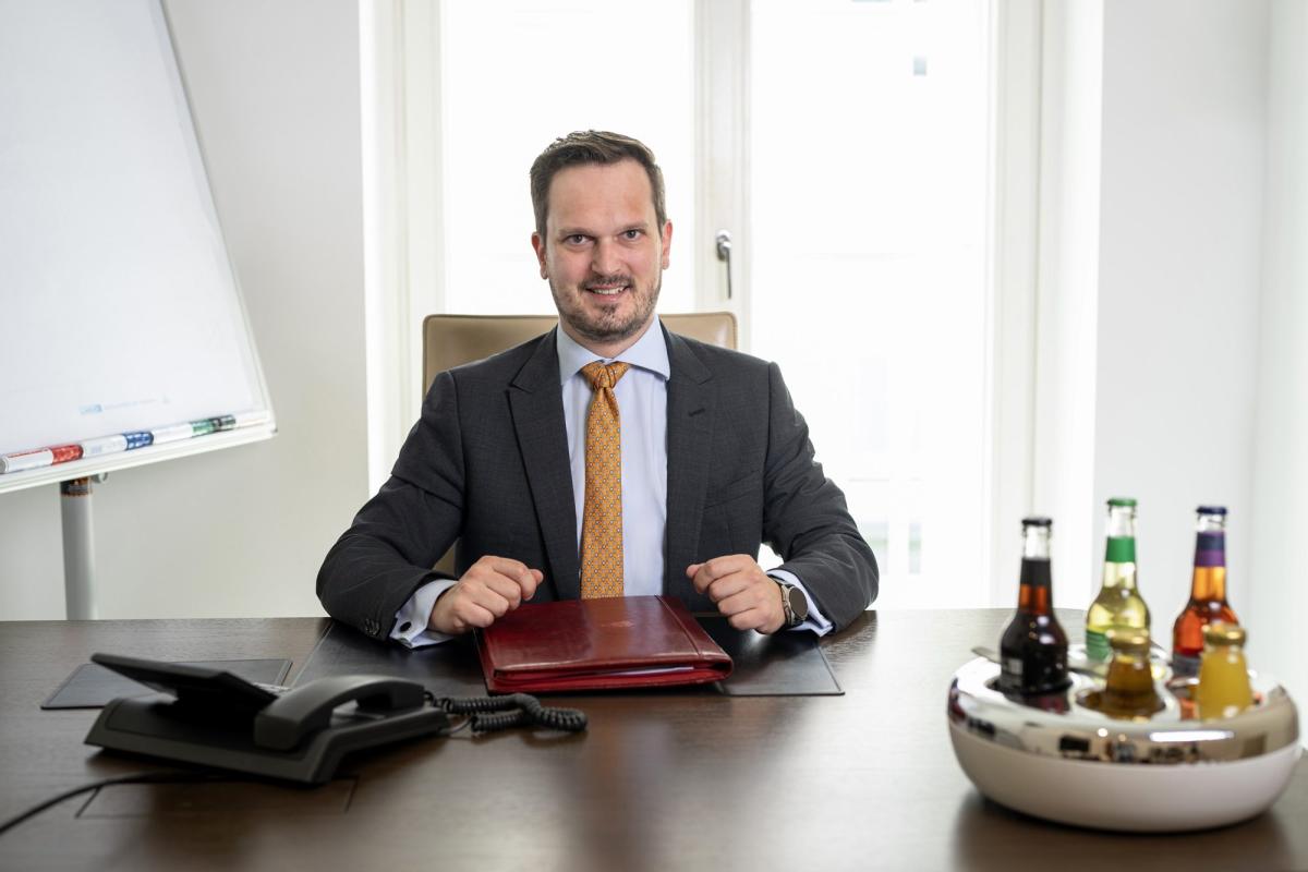 Ein Unternehmer im Anzug sitzt an einem Tisch und lächelt, während er in der Friendzone ist.