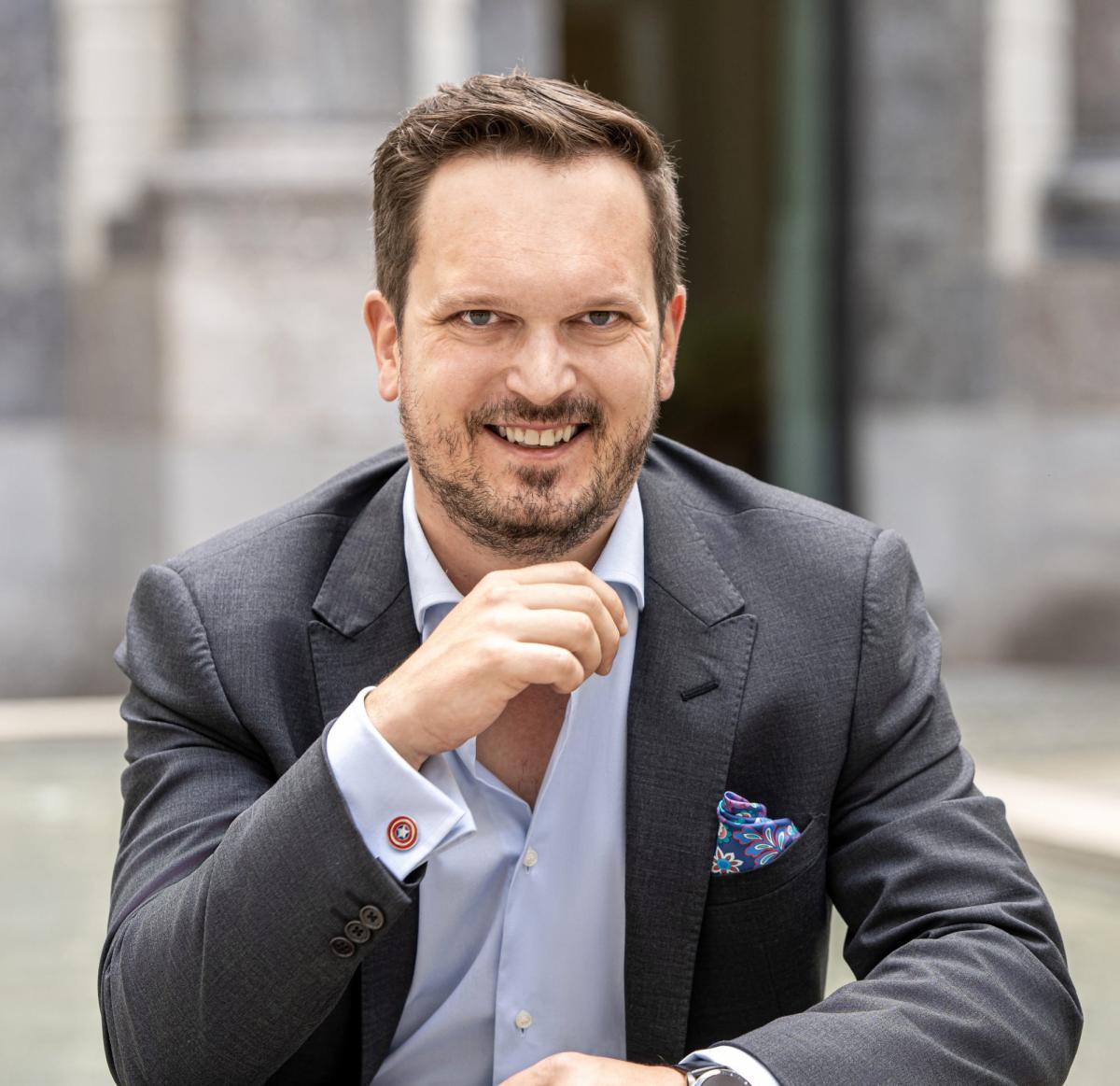 Mann im Anzug mit Lächeln, der über Werte in Partnerschaften reflektiert.
