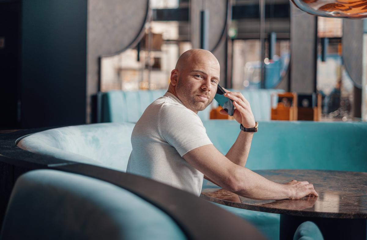 Mann im Café, der am Telefon spricht, analysiert den Sales-Stellenmarkt 2026.