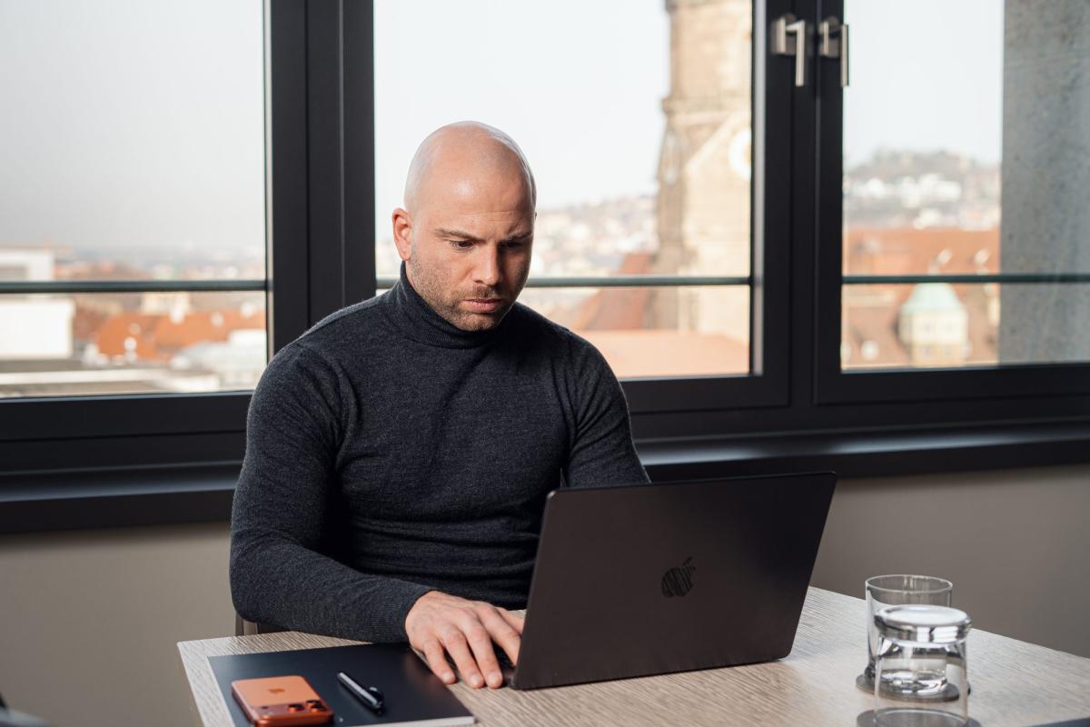 Mann arbeitet am Notebook mit Blick auf die Stadt, Vertriebler im Mittelstand.