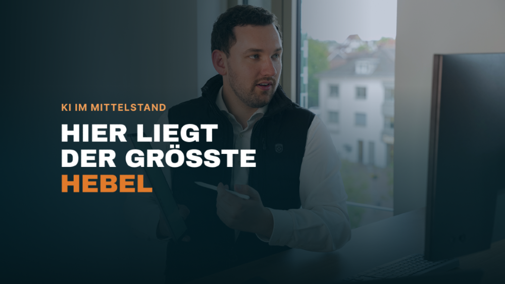 Mann zeigt in einem Büro auf den Bildschirm und erklärt KI im Mittelstand.