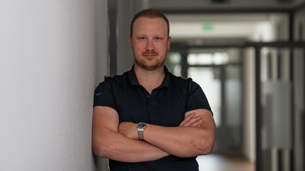 Ein Mann steht mit verschränkten Armen im Büro – menschliche Firewall als Schutz vor Social Engineering.